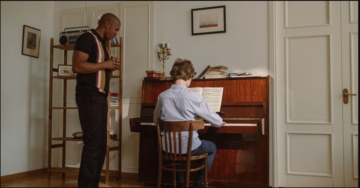 Profesor acompañando a un alumno durante una clase de piano