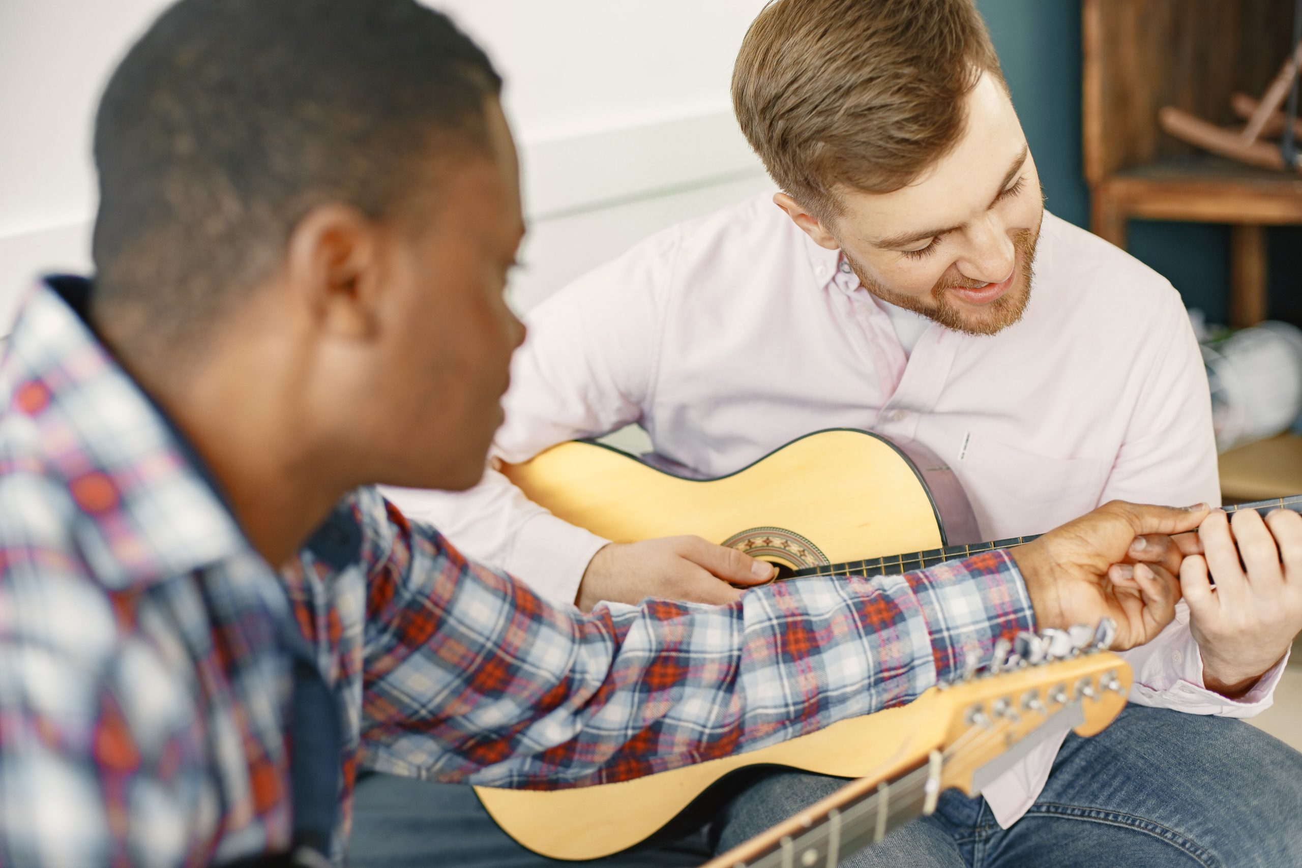 Dos adultos aprendiendo guitarra en una clase de música